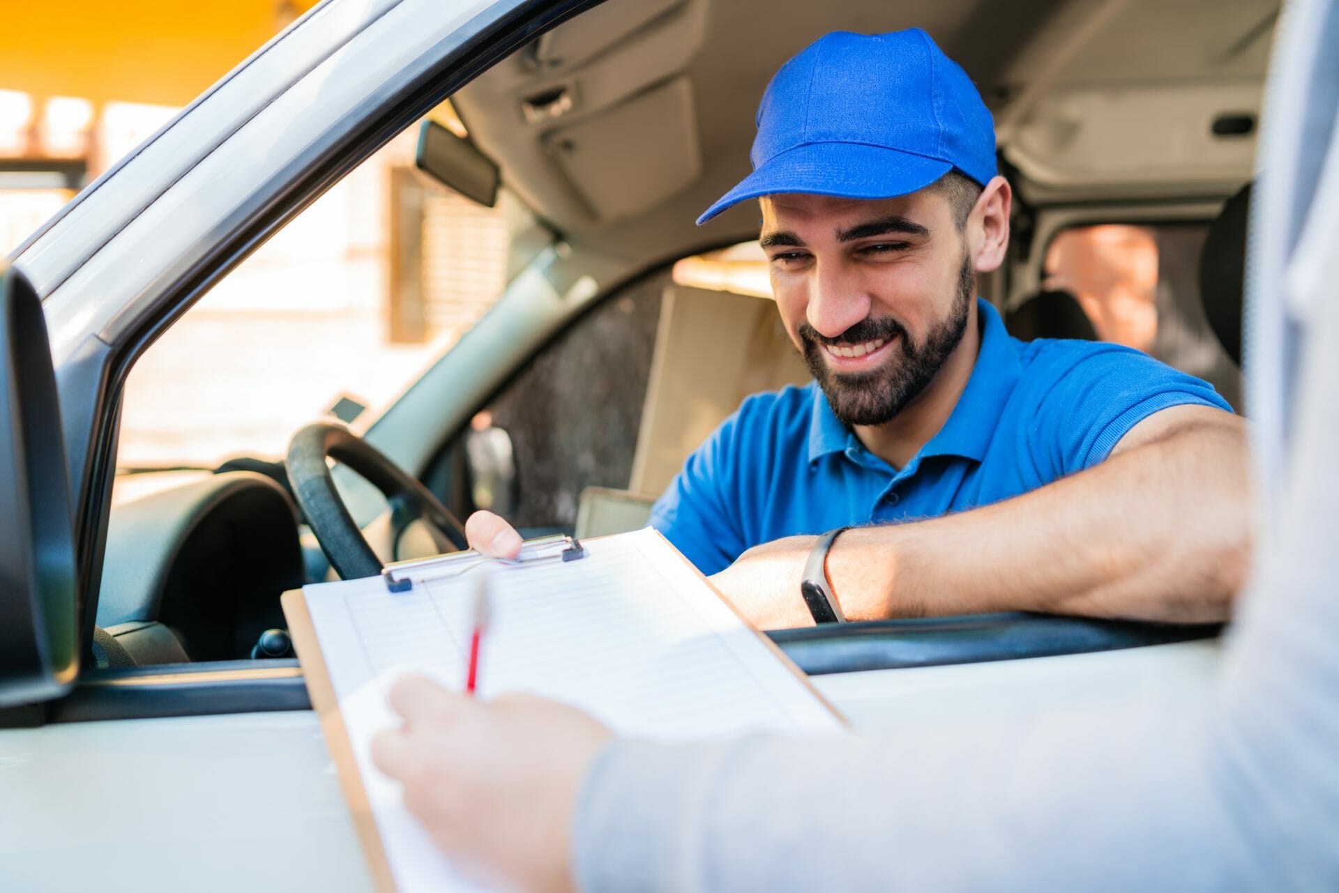 Delivery man in van while customer sign in clipboard.